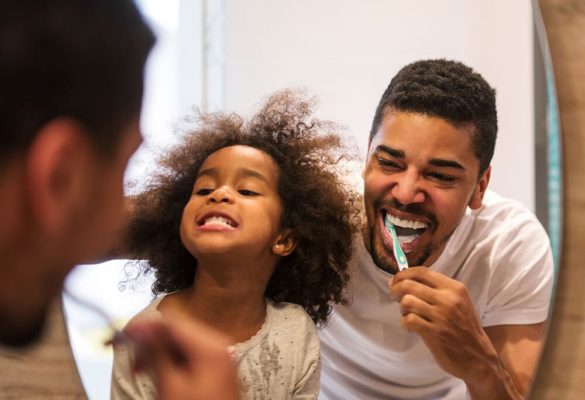 Father and daughter brush their teeth in the bathroom with clean, filtered water.