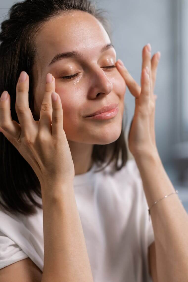 Woman touches the soft, healthy skin on her face thanks to clean, filtered water at home.