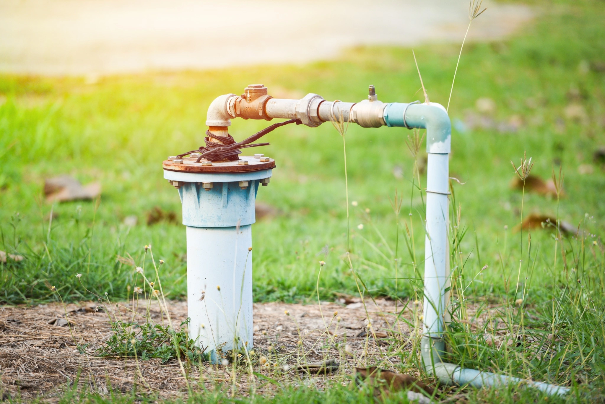 Private well head and water pipe in a yard representing residential well water systems in New Hampshire