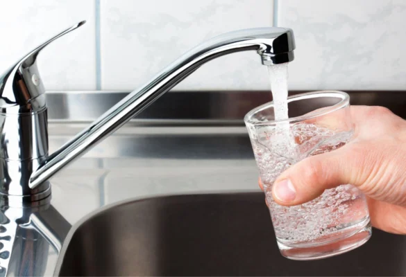Pouring water from a faucet in the kitchen into a glass