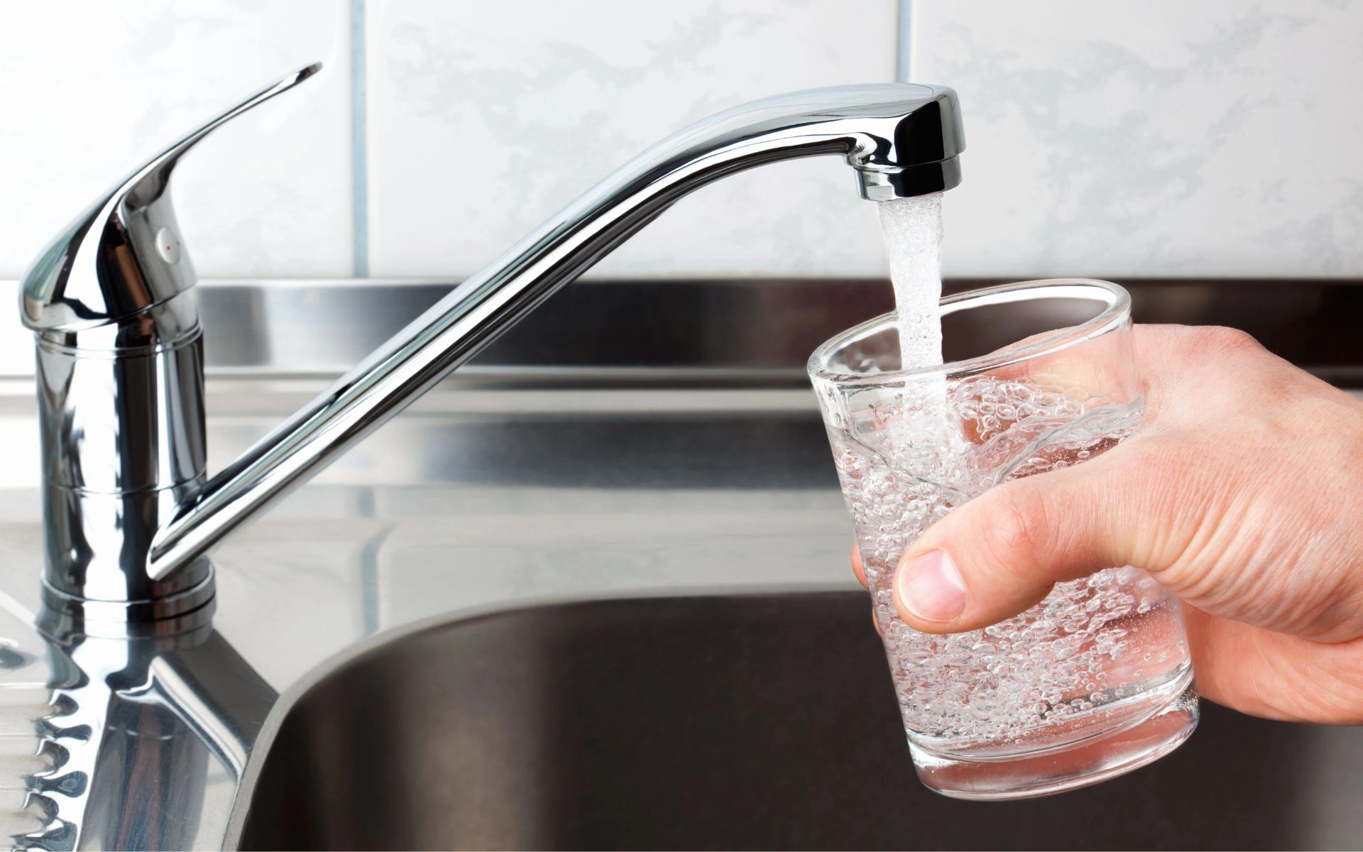 Pouring water from a faucet in the kitchen into a glass