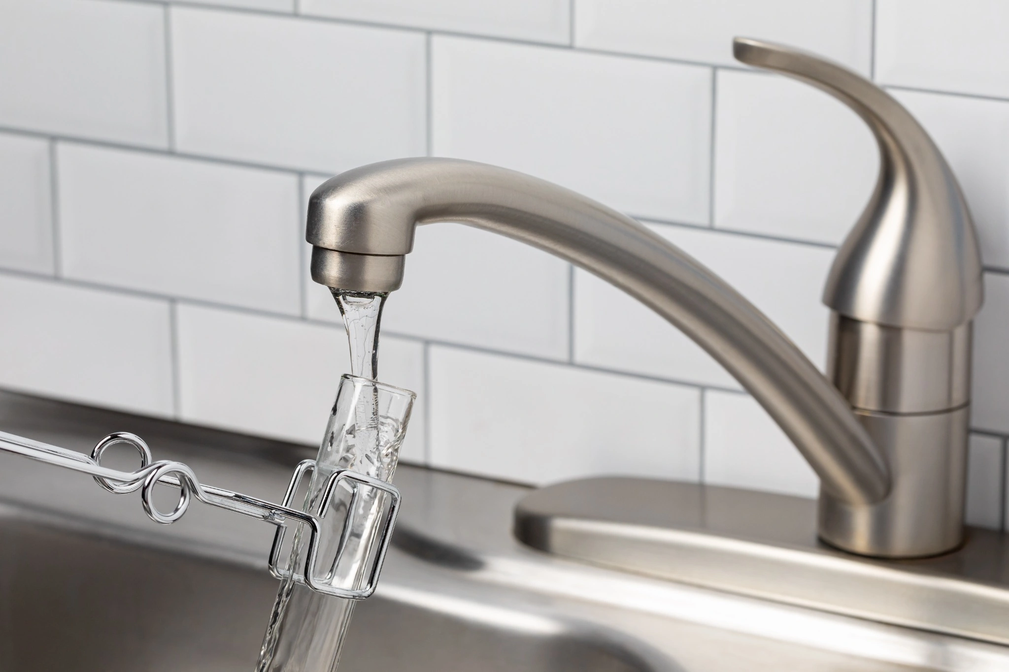 Collecting a water sample from a kitchen faucet for well water testing during a New Hampshire home inspection