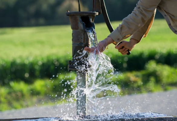 Person pumping water from a private well illustrating groundwater sources and arsenic concerns in New Hampshire well water