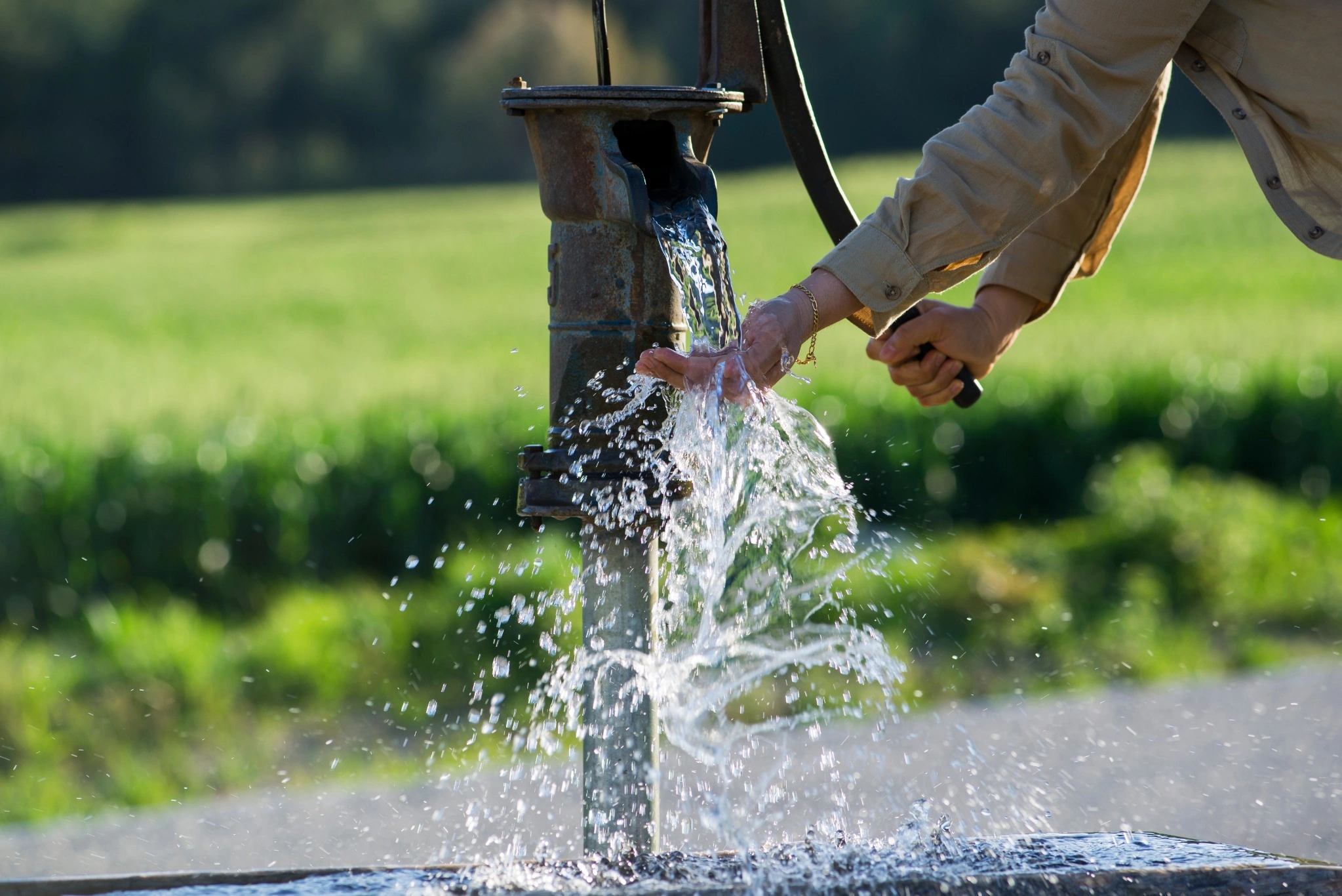 Person pumping water from a private well illustrating groundwater sources and arsenic concerns in New Hampshire well water